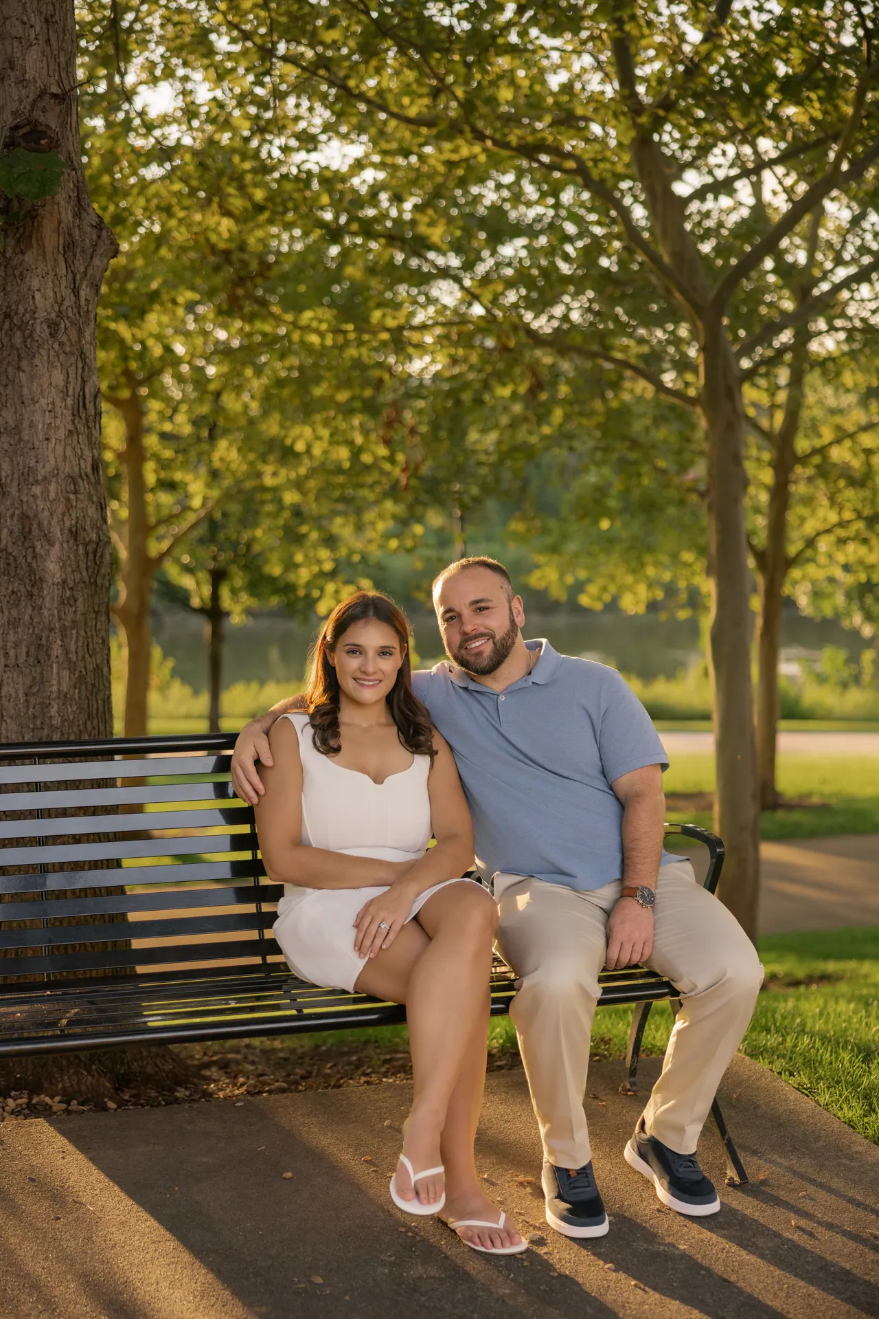 Kevin and Sarina sitting on a park bench under green trees