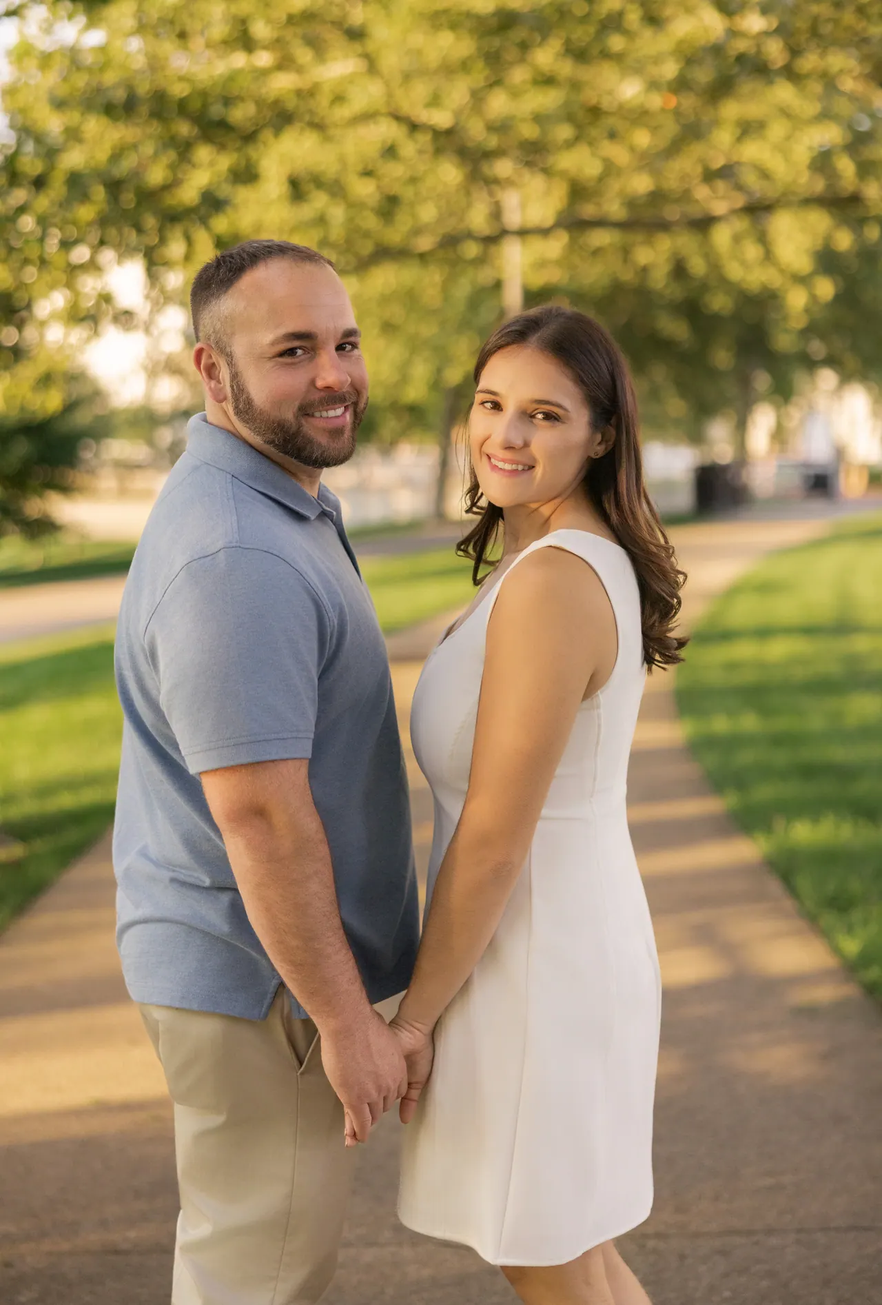 Kevin and Sarina holding hands on a sunny park path